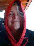photo of Kiya Heartwood peering out from within a red hooded sweatshirt