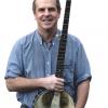 photo of Tom Rawson holding his banjo and smiling