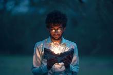 Man looking at an open book with glowing fiberoptic lights