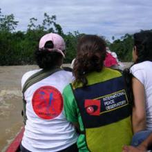 photo of three members of the IPO in a boat on a muddy river