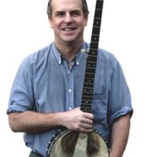 photo of Tom Rawson holding his banjo and smiling